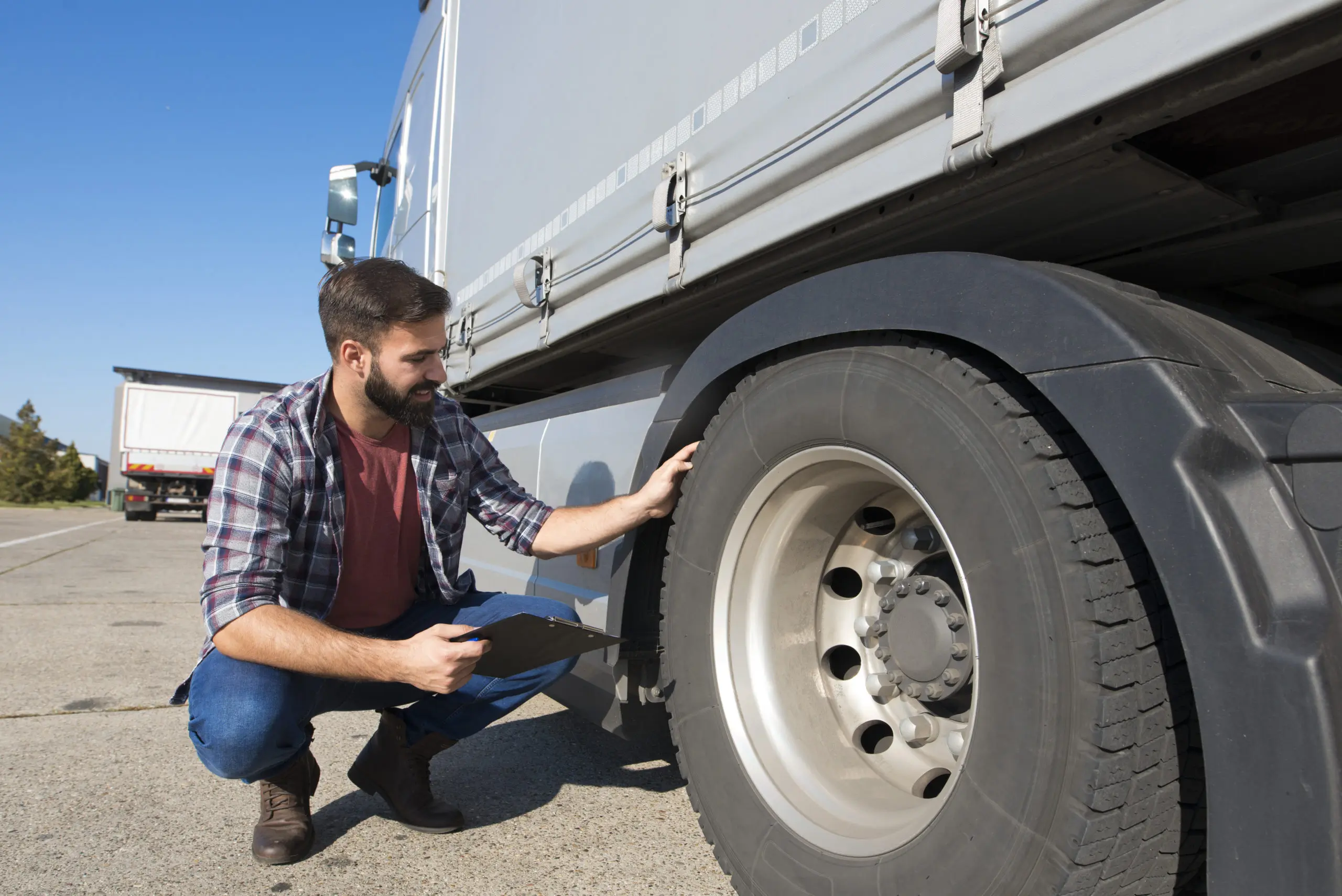 Chauffeur contrôlant l’usure d’un pneu de son camion